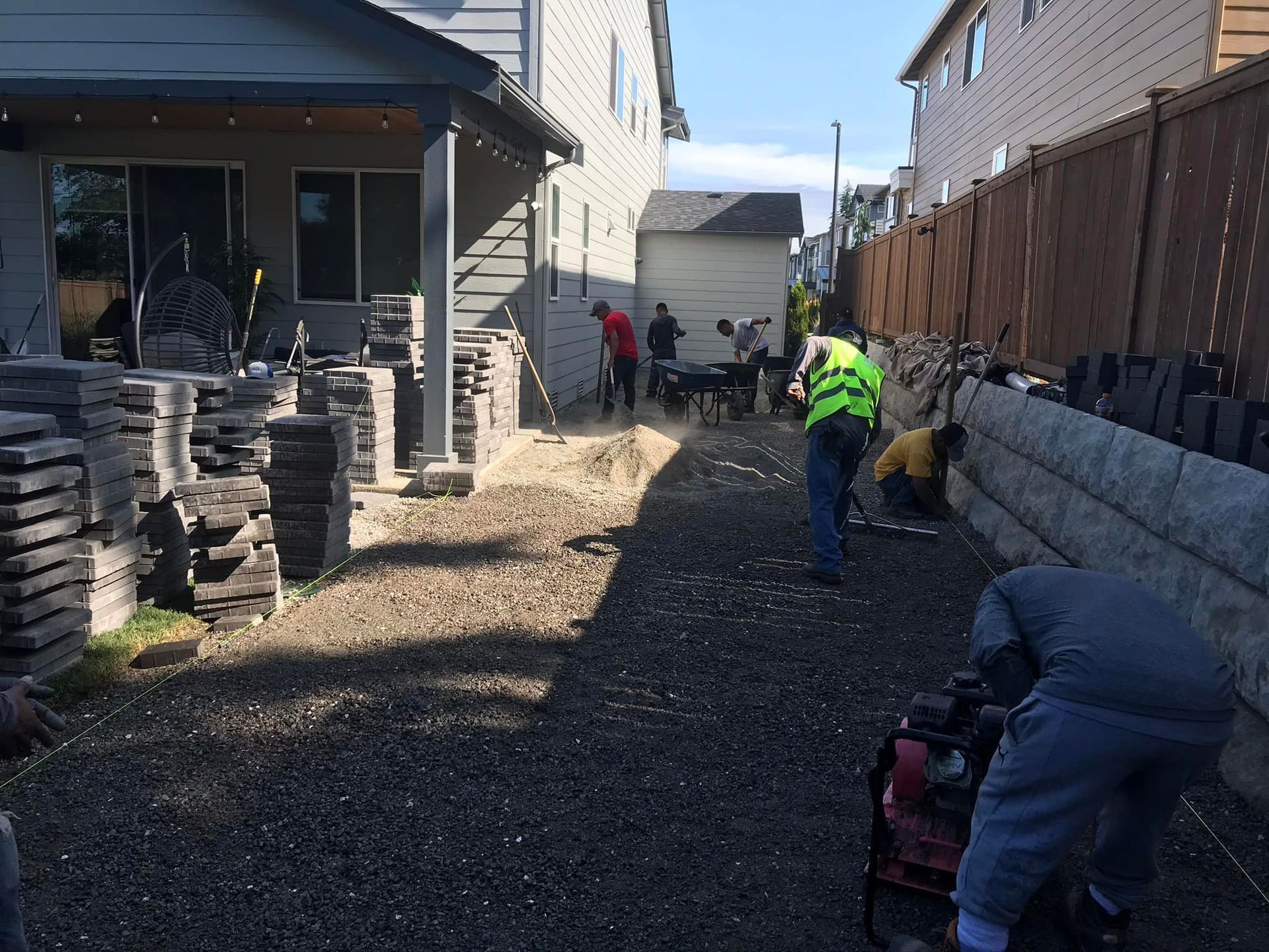 A group of people are working on a driveway in front of a house.