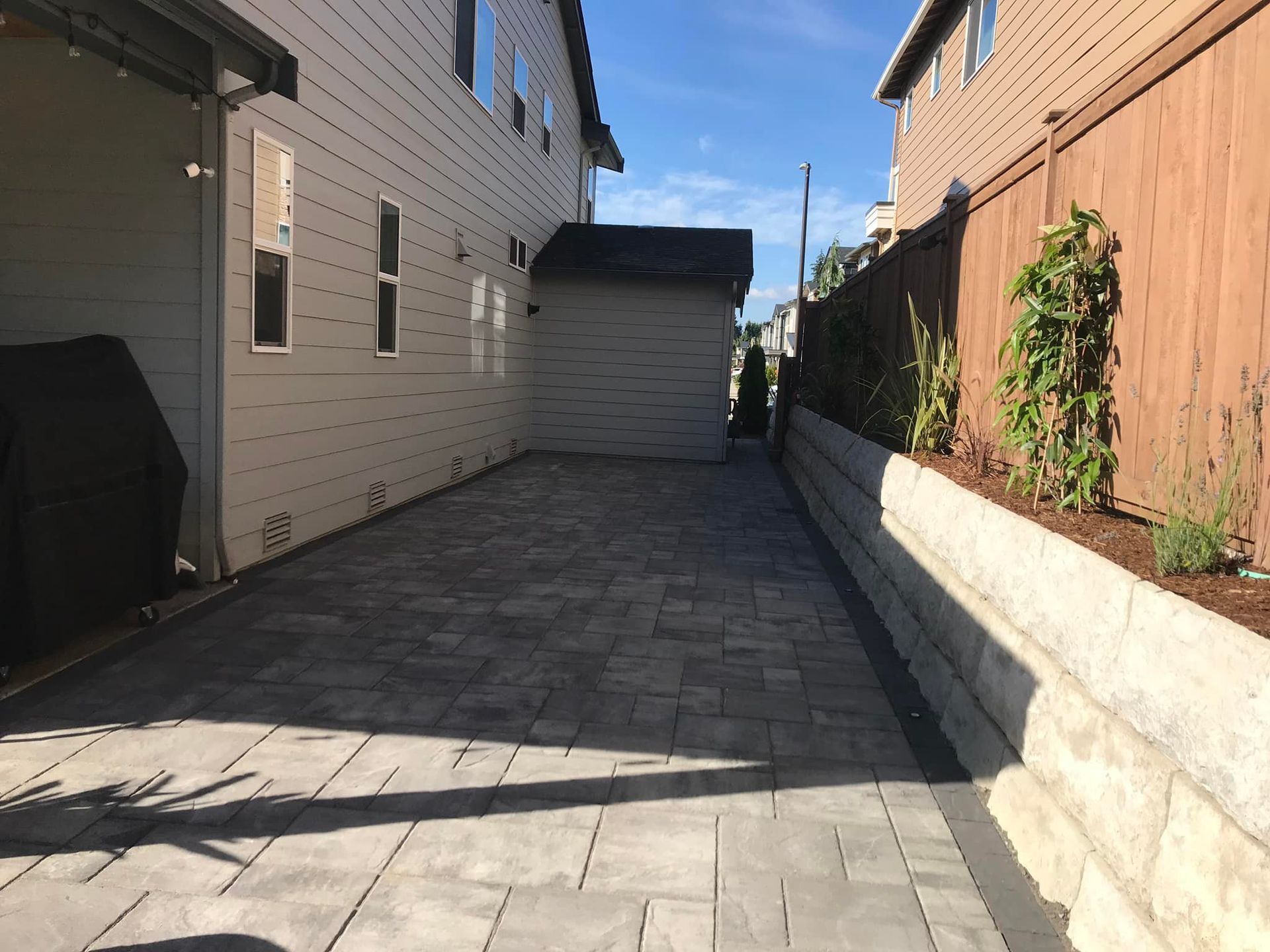 A driveway between two houses with a garage and a fence.