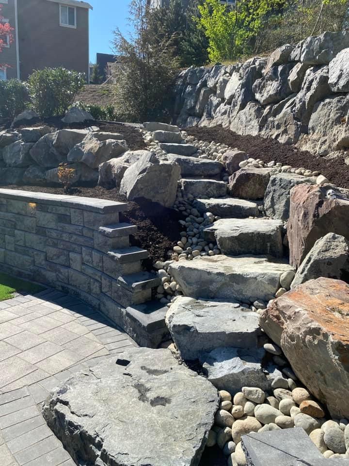 A stone wall with stairs leading up to it surrounded by rocks.