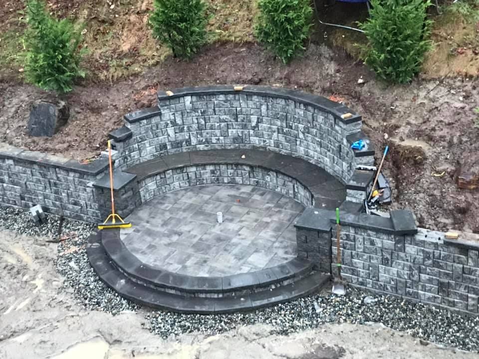 A stone wall with a circular patio in the middle of it.