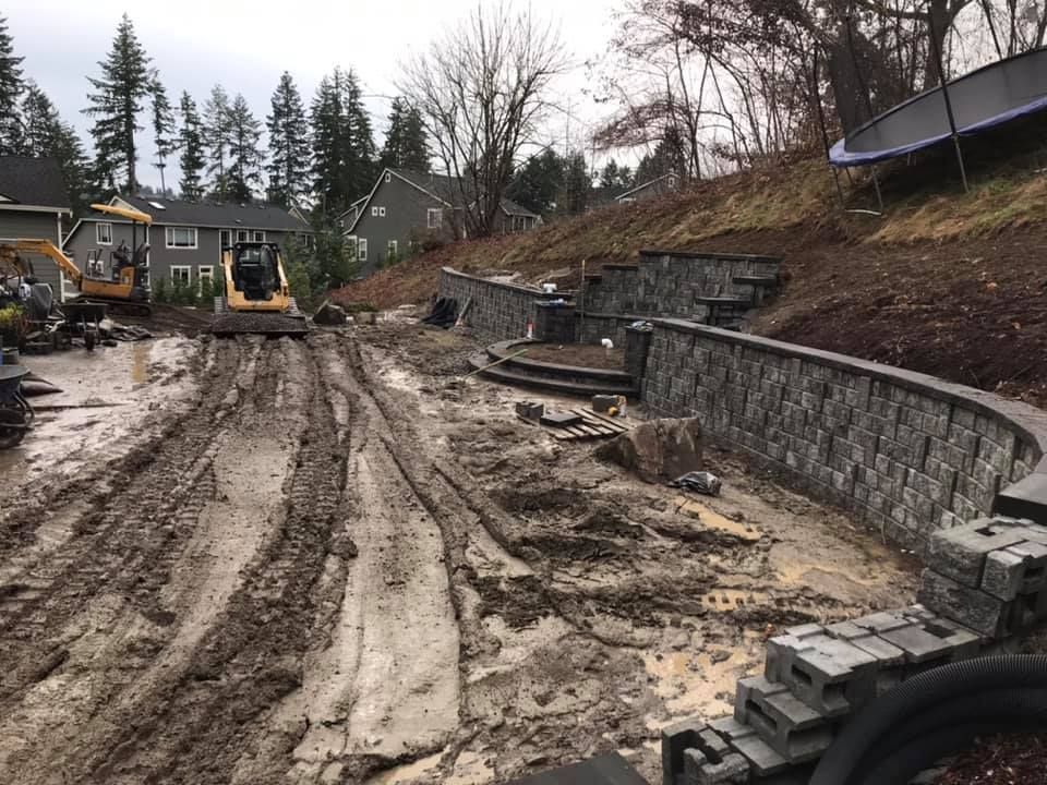 A construction site with a lot of dirt and a house in the background.