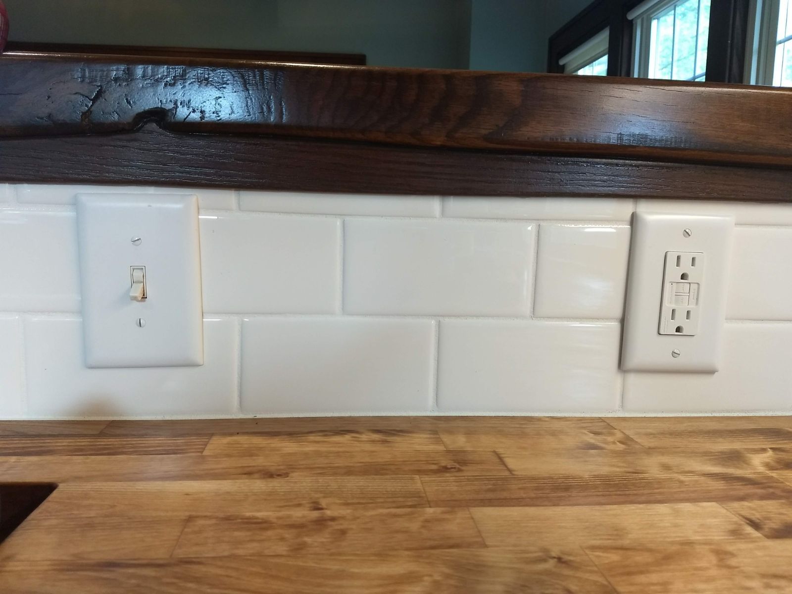 A kitchen counter with two electrical outlets and two light switches