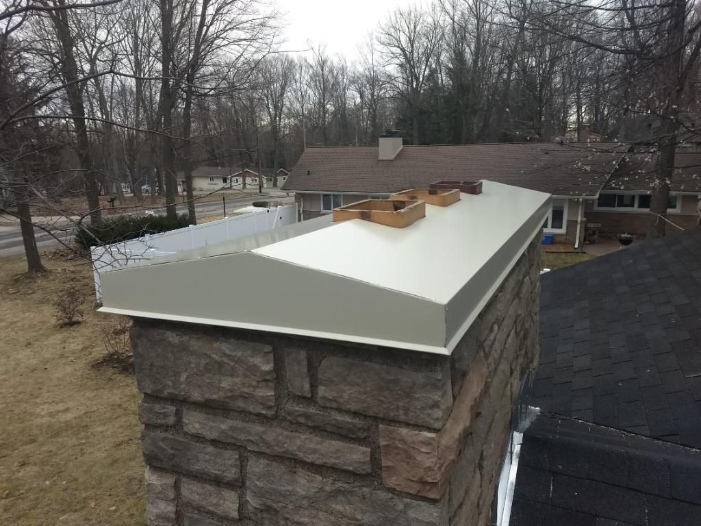 A brick chimney with a metal cap on top of it.