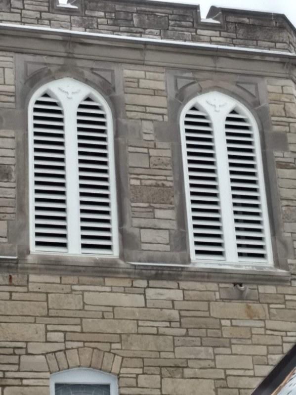 A brick building with two arched windows with white shutters