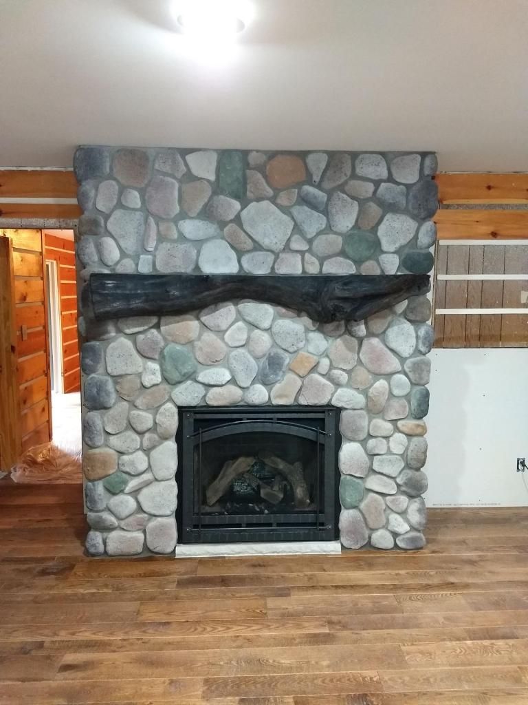 A stone fireplace with a wooden mantle in a living room.