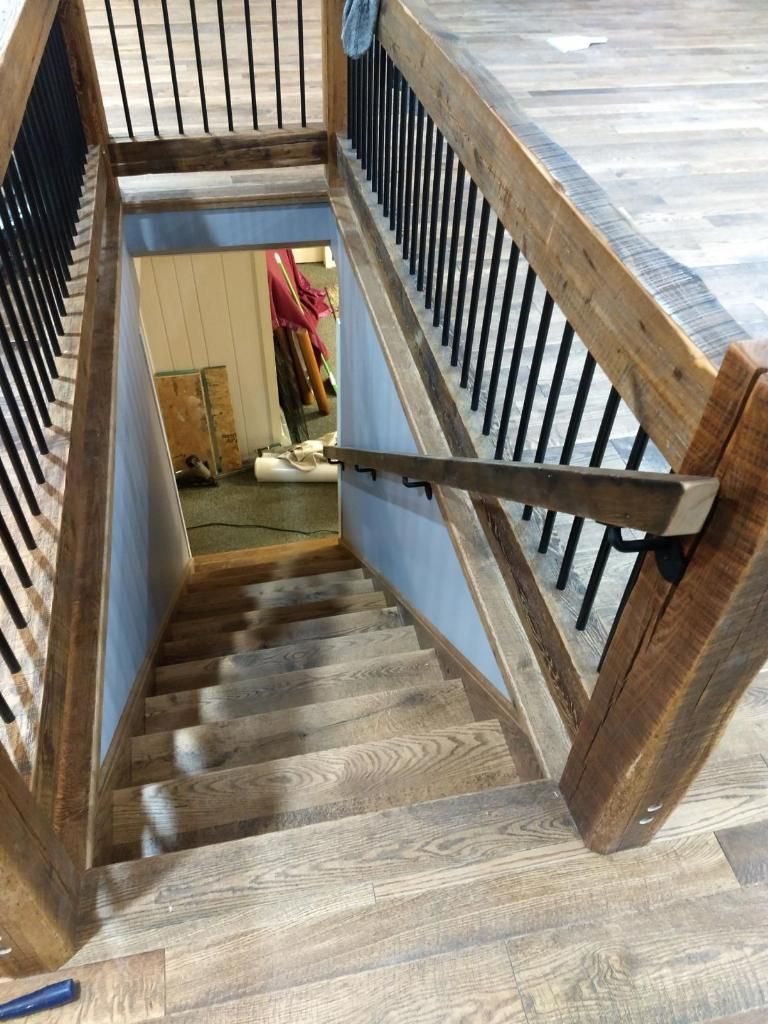 A wooden staircase with a metal railing leading to a basement.