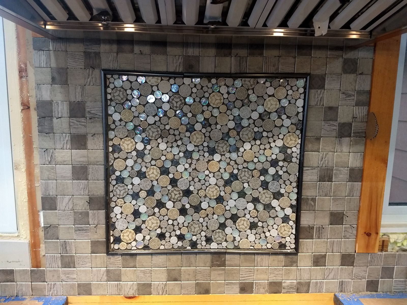 A picture is hanging on a tiled wall in a kitchen