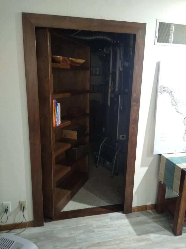 A room with a bookshelf and a door that leads to a basement.