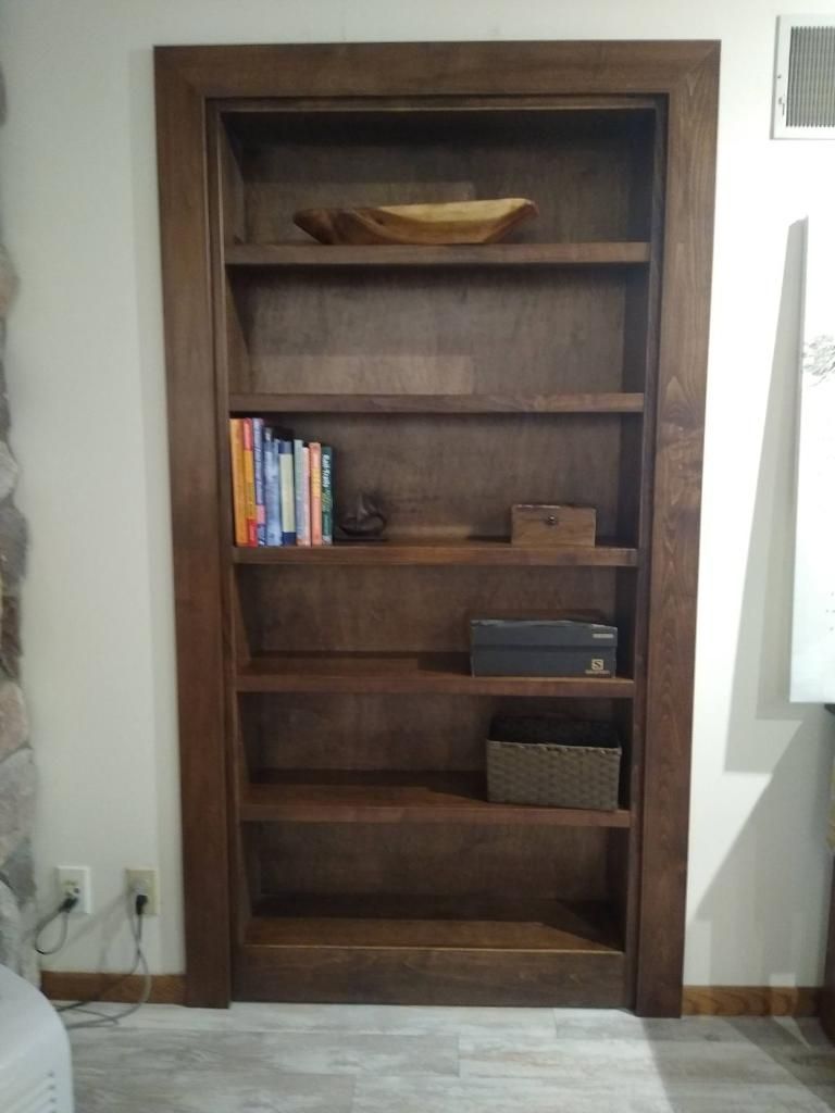 A wooden bookshelf with books and a bowl on top of it.