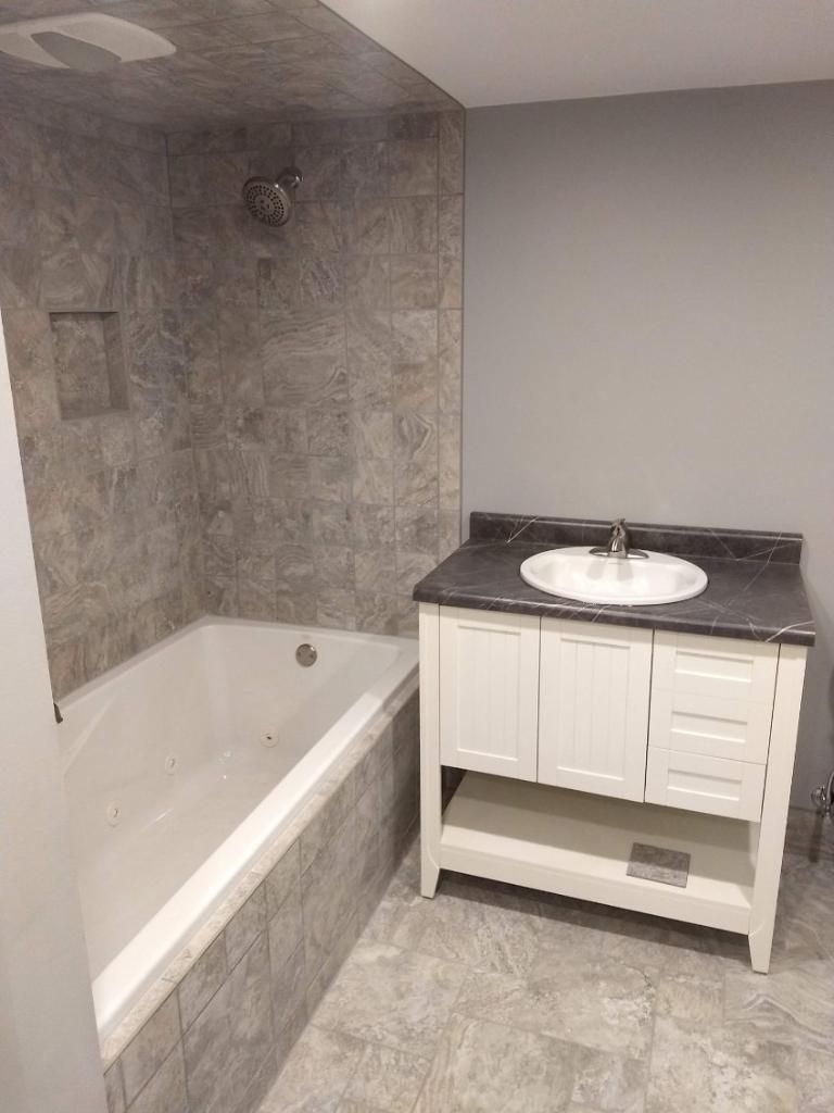 A bathroom with a bathtub , sink , and shower.