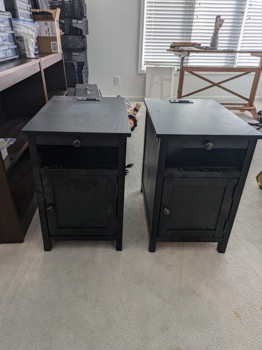 Two black nightstands are sitting next to each other in a living room.