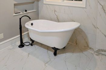 A white bathtub is sitting in a bathroom next to a black faucet.