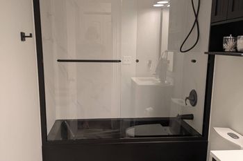 A bathroom with a black tub and a glass shower door.