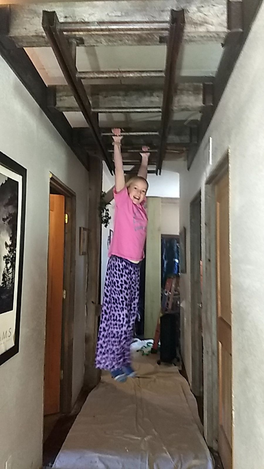 Monkey bars installed in this interior hallway were made from barn beams, metal track, and repurposed cattle stanchion.