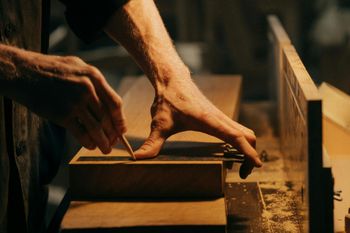 A man is measuring a piece of wood with a tape measure.