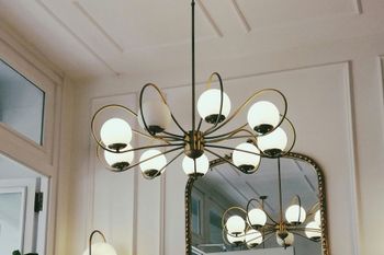 A chandelier is hanging from the ceiling next to a mirror