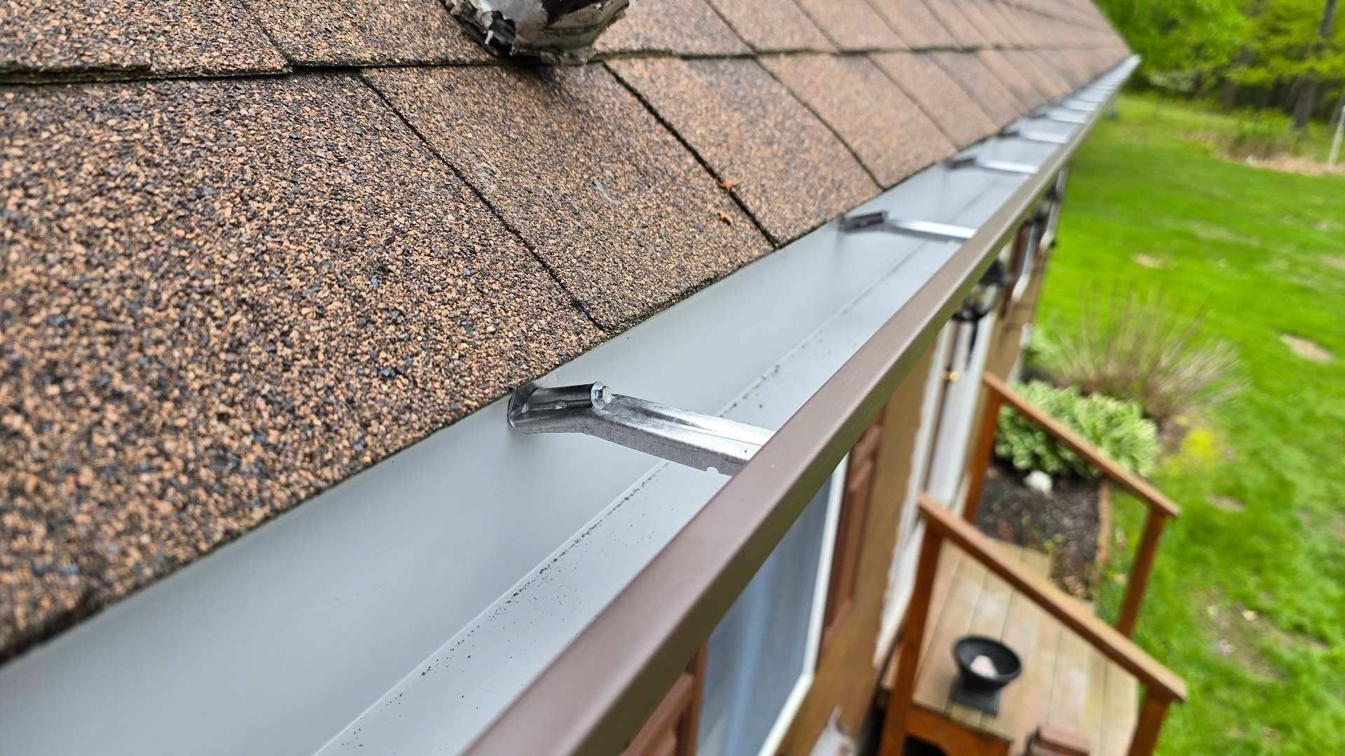Brown roof with attached dark gutter; supported by silver clips.