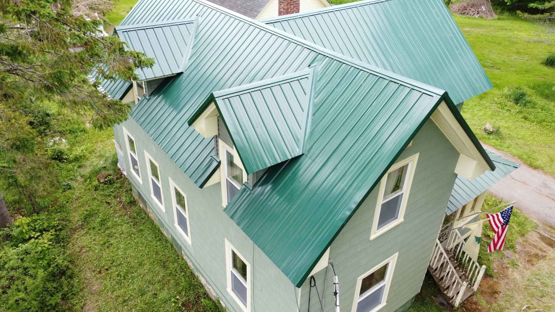 Green house with metal roof and American flag.