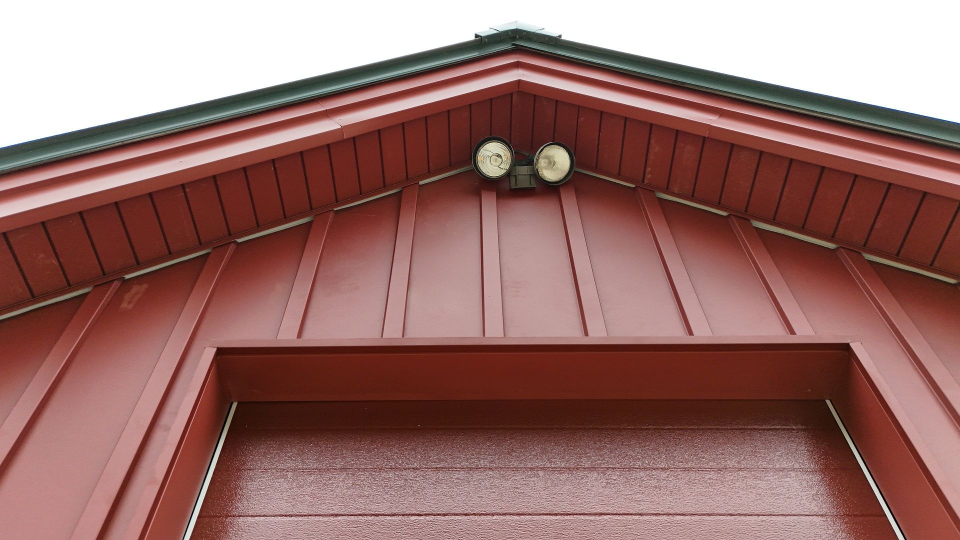Red building with a garage door and overhead lights.