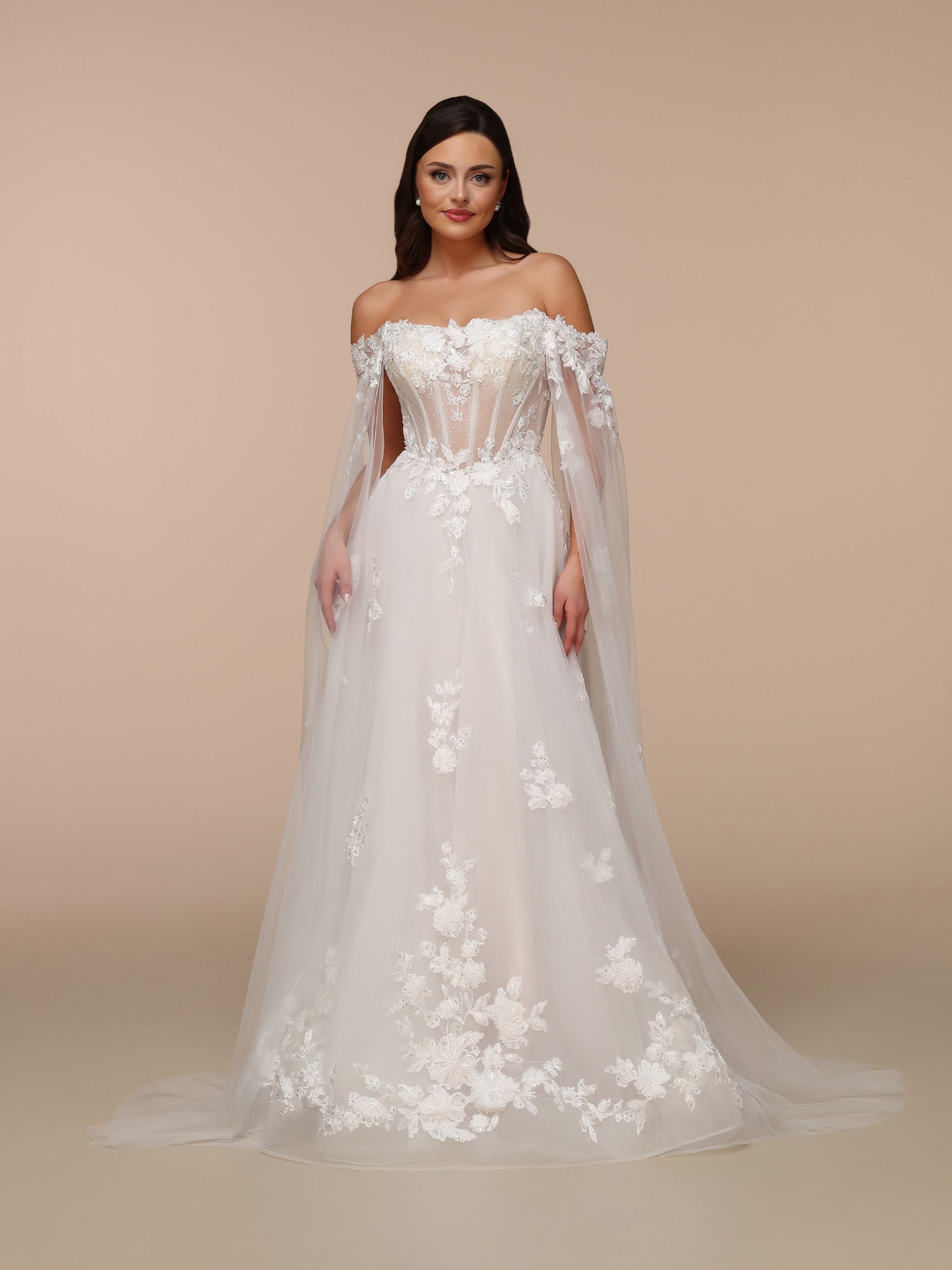 Woman in a white off-the-shoulder wedding dress with floral embellishments and a flowing train.