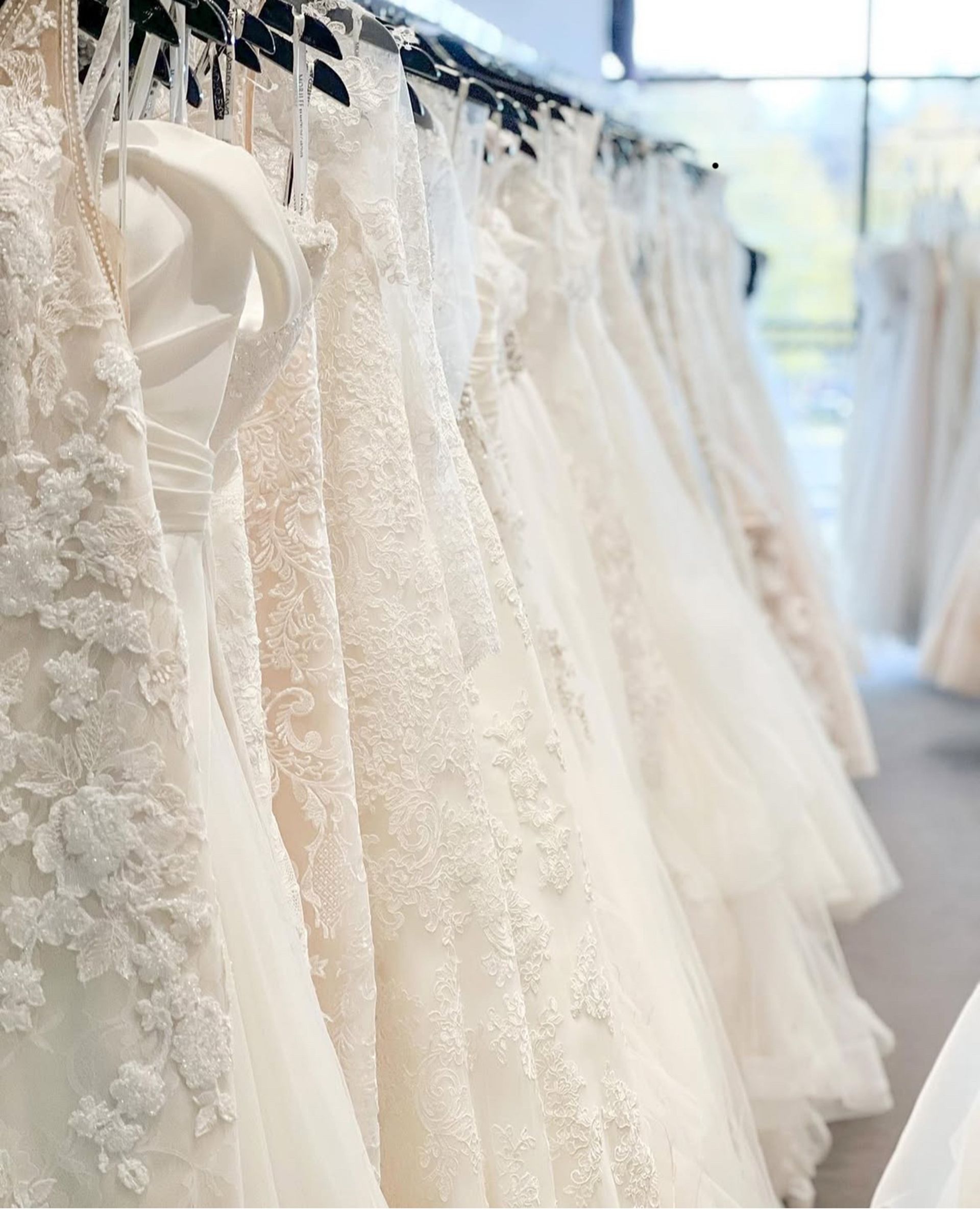 Bride in white gown and veil on ornate stone steps, holding bouquet.