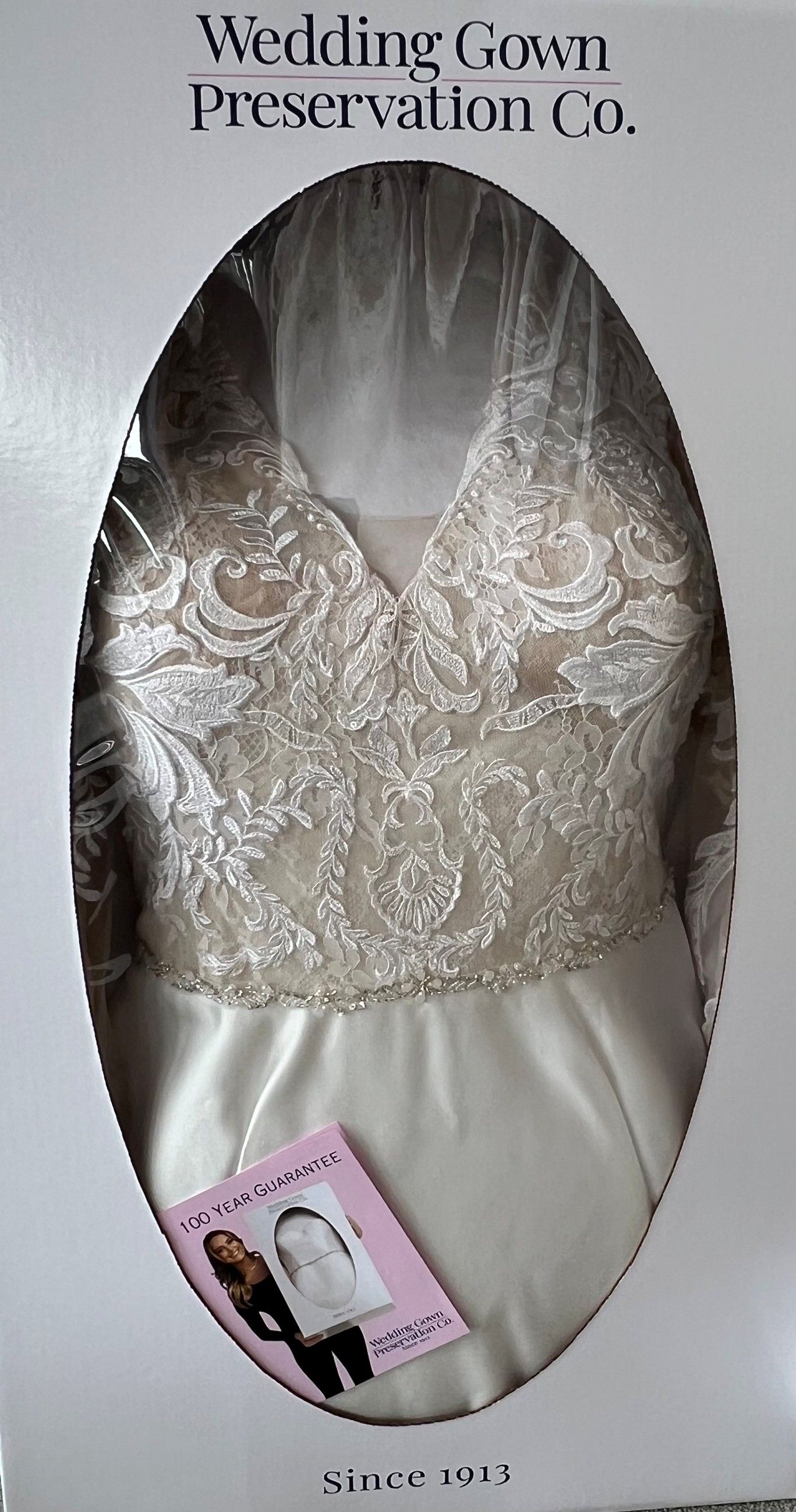 Wedding gown in preservation box. White dress with embellished bodice, visible through plastic.