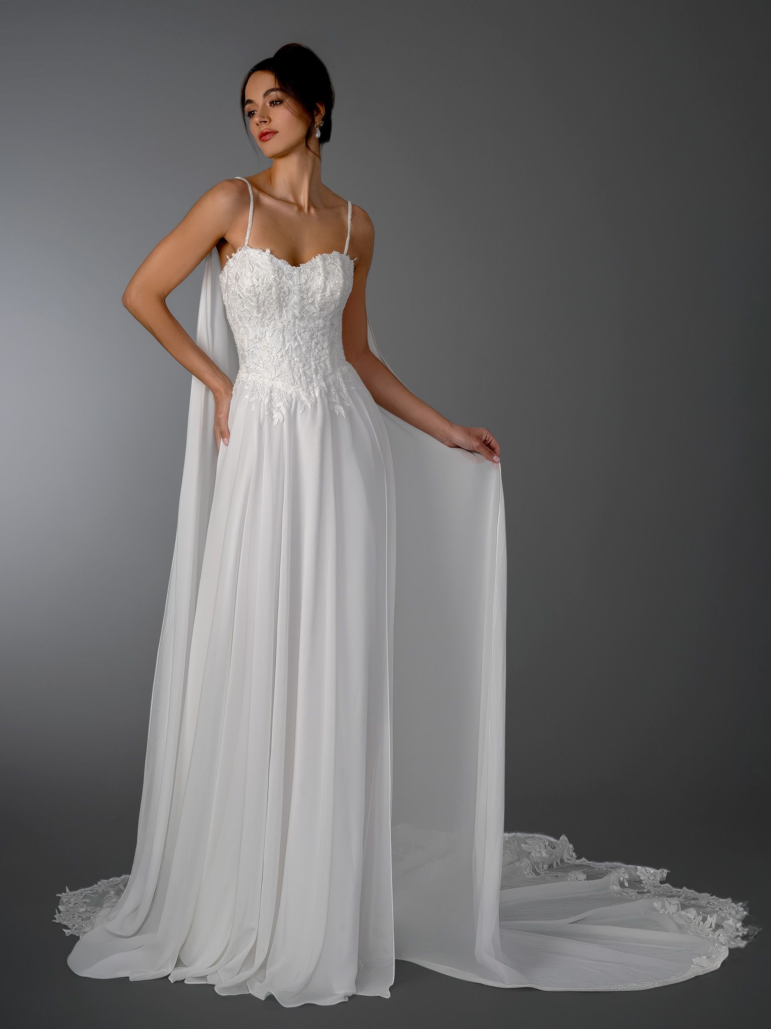 Woman in a white wedding dress with a decorated bodice, spaghetti straps, and a long train.