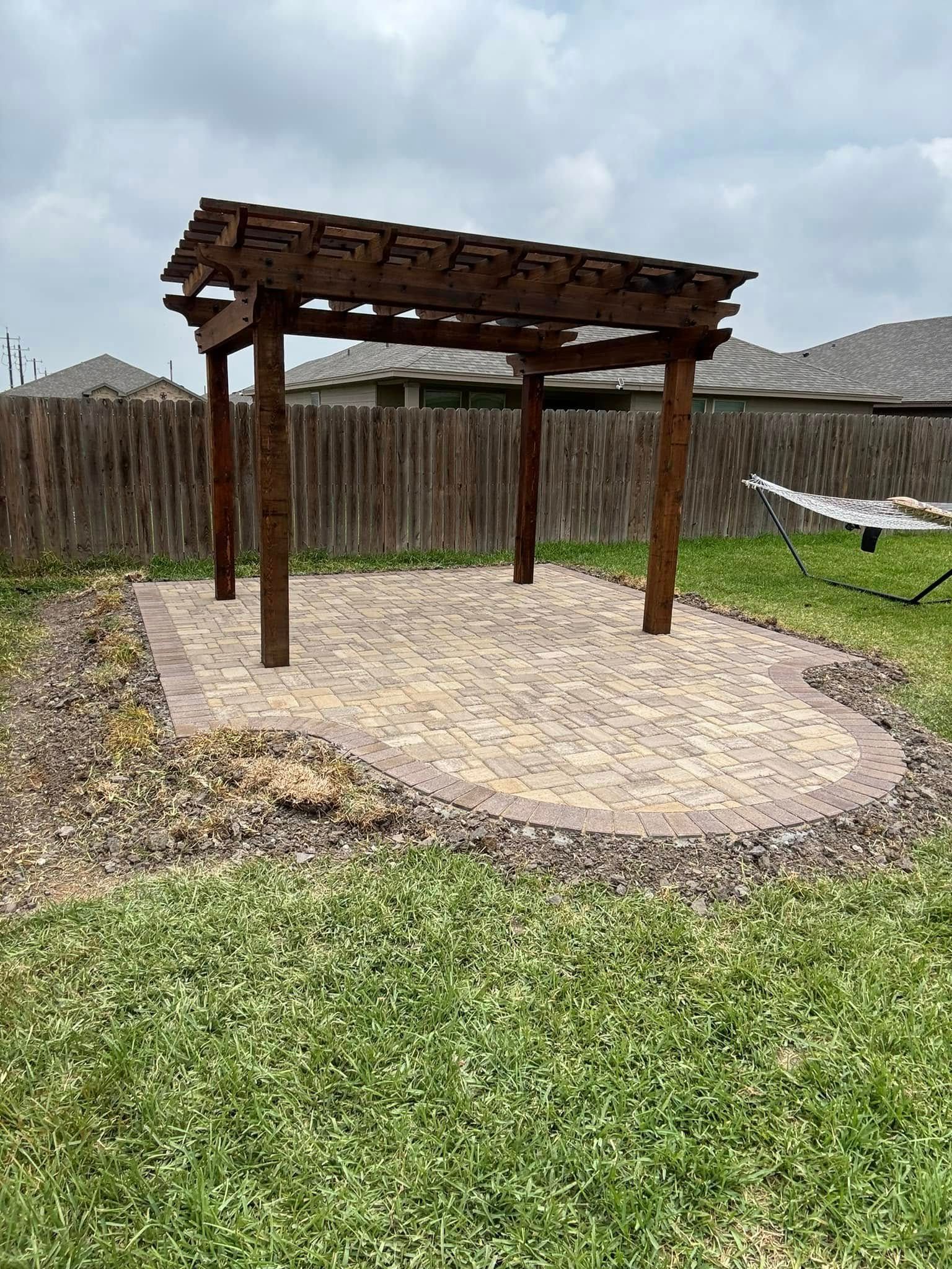 A wooden pergola is sitting in the middle of a lush green yard.