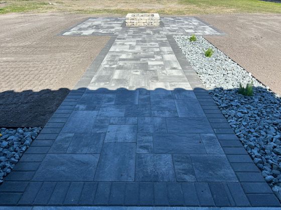 A brick walkway leading to a gravel area surrounded by rocks.
