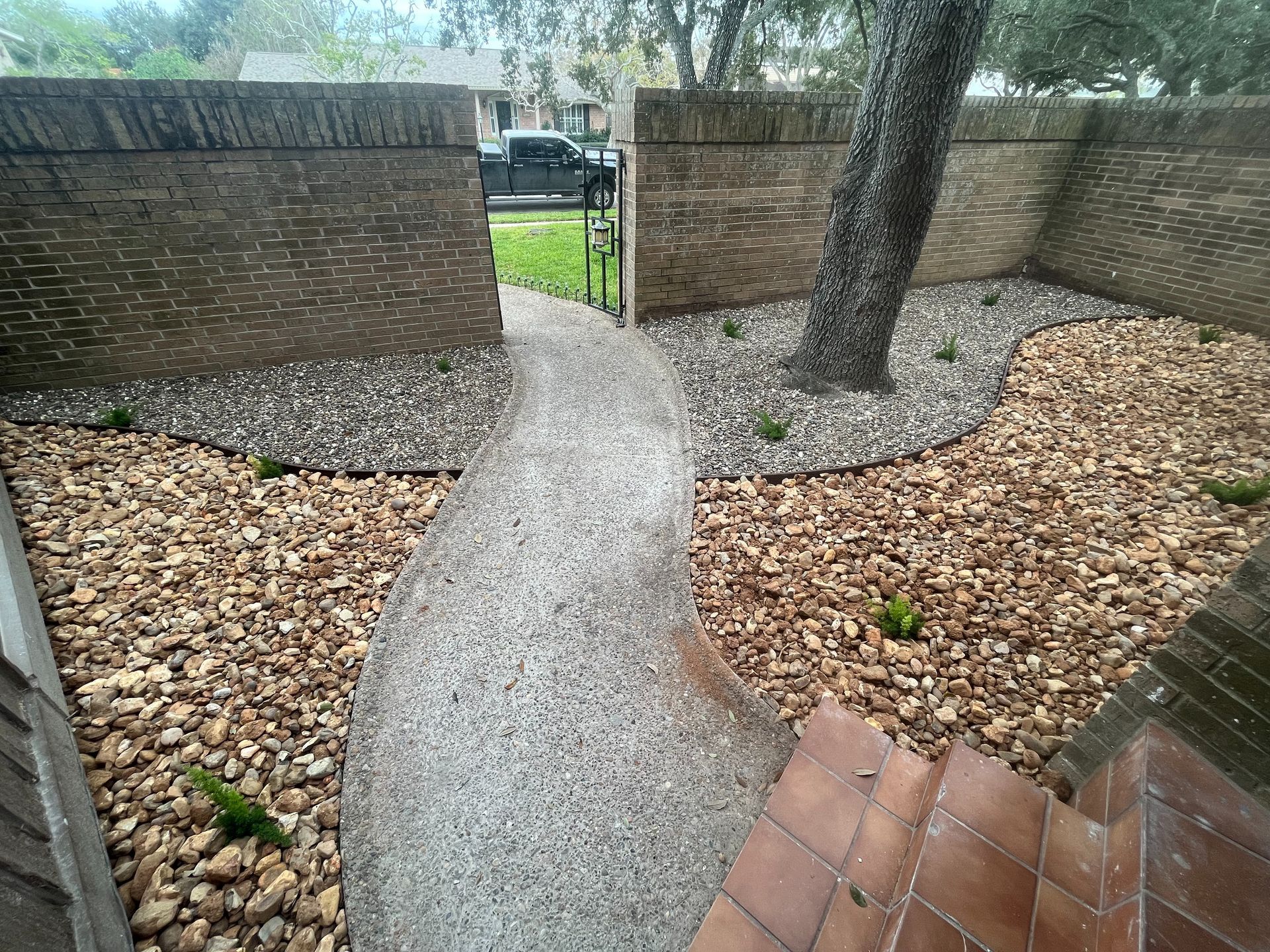 A walkway leading to a backyard filled with rocks and mulch.