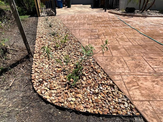 A concrete walkway with a gravel border and a hose.