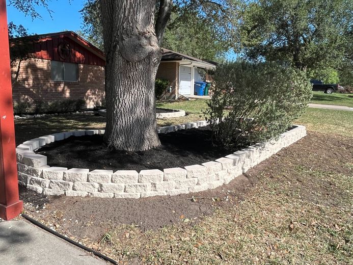 A tree is surrounded by a stone wall in front of a house.
