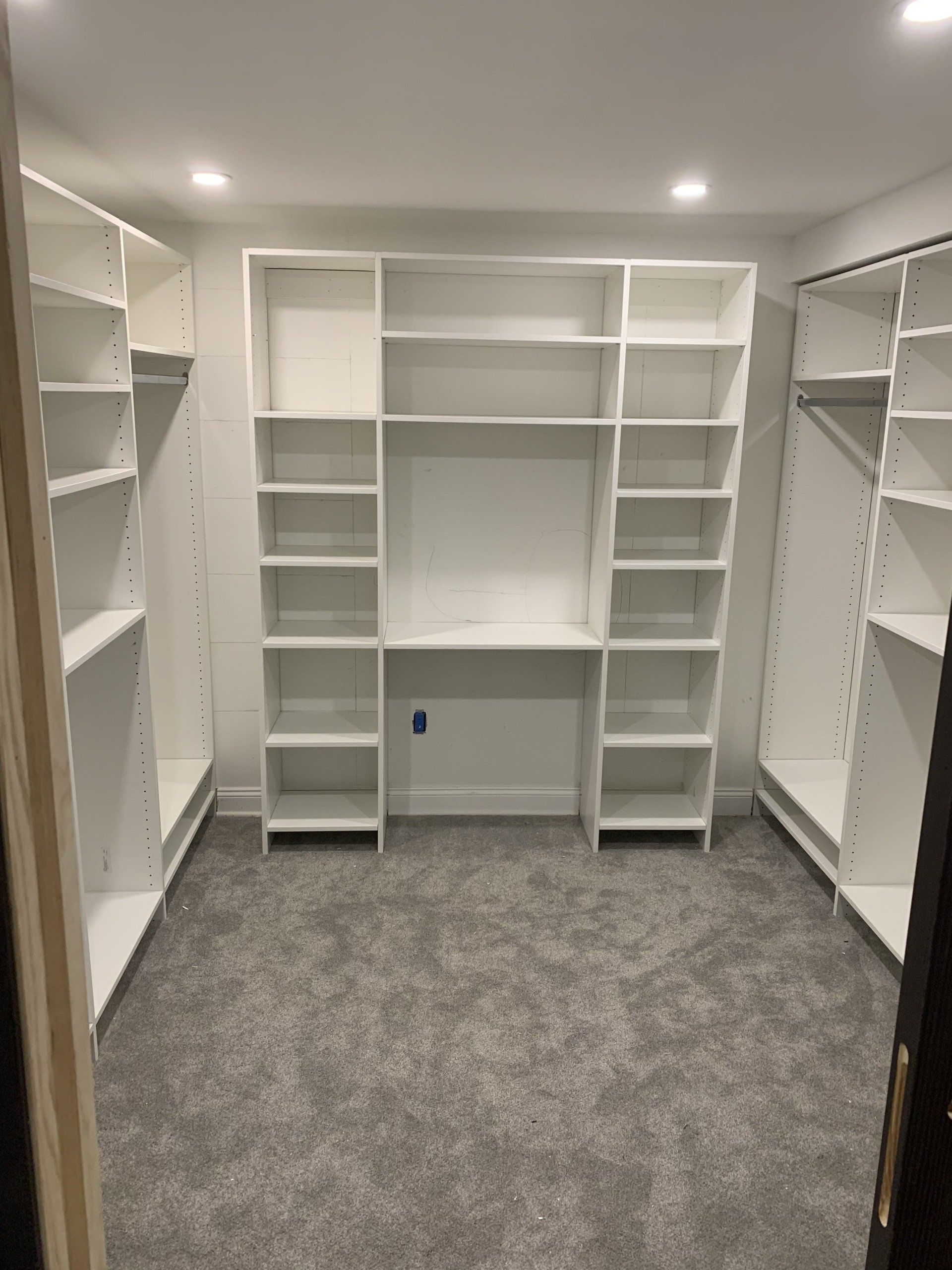 White shelving unit built into a closet with gray carpet.
