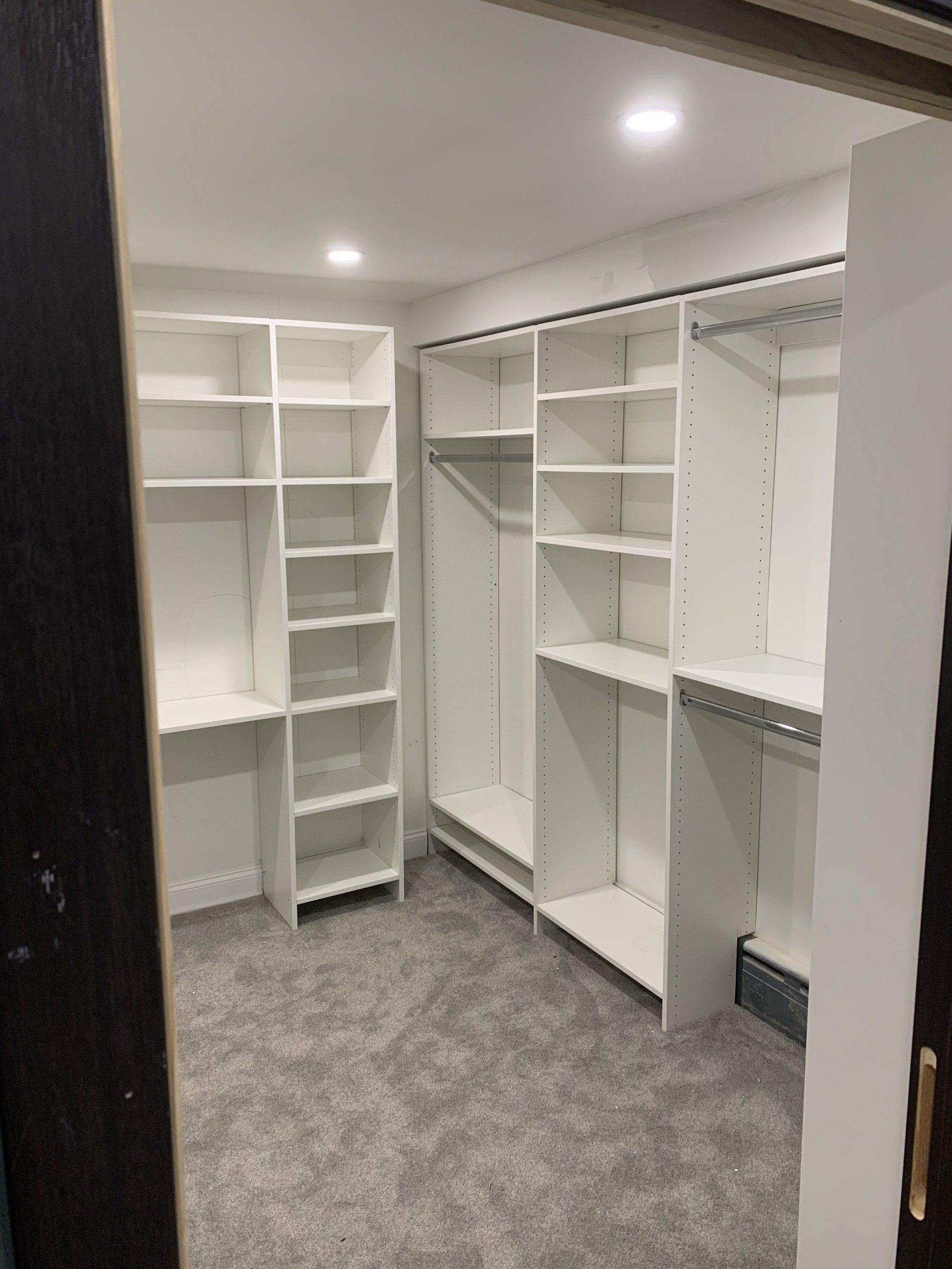 White closet shelving in a newly remodeled space, with gray carpet and overhead lighting.