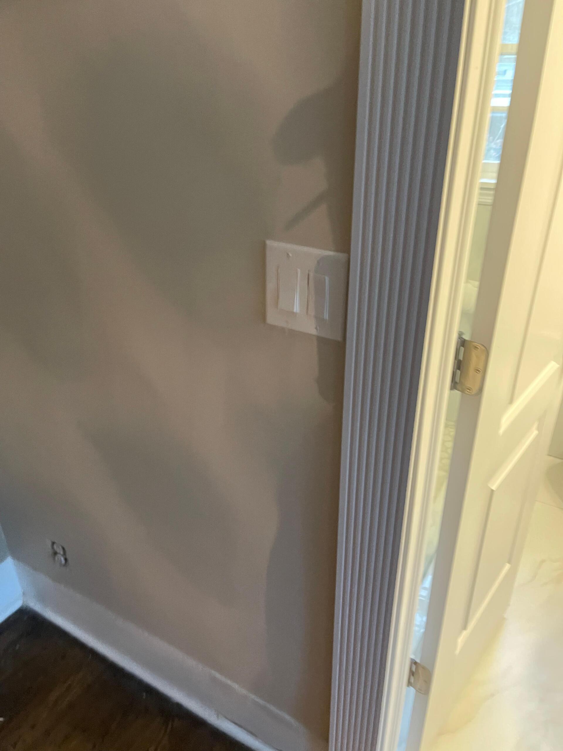 Light switch on a beige wall, next to a white door frame.