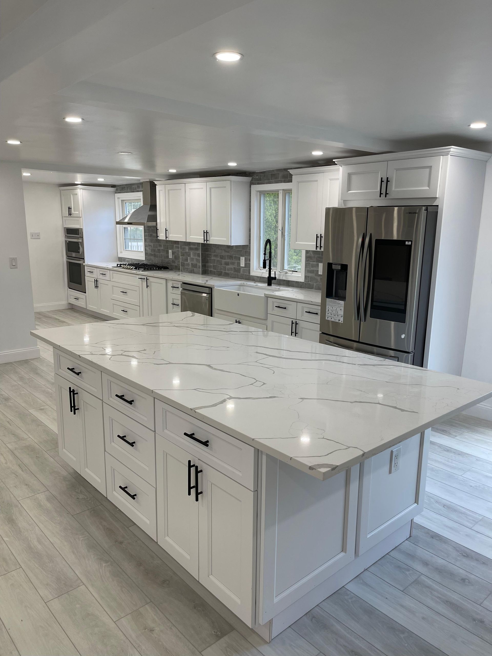 Modern white kitchen with island, stainless steel appliances, and white cabinets.