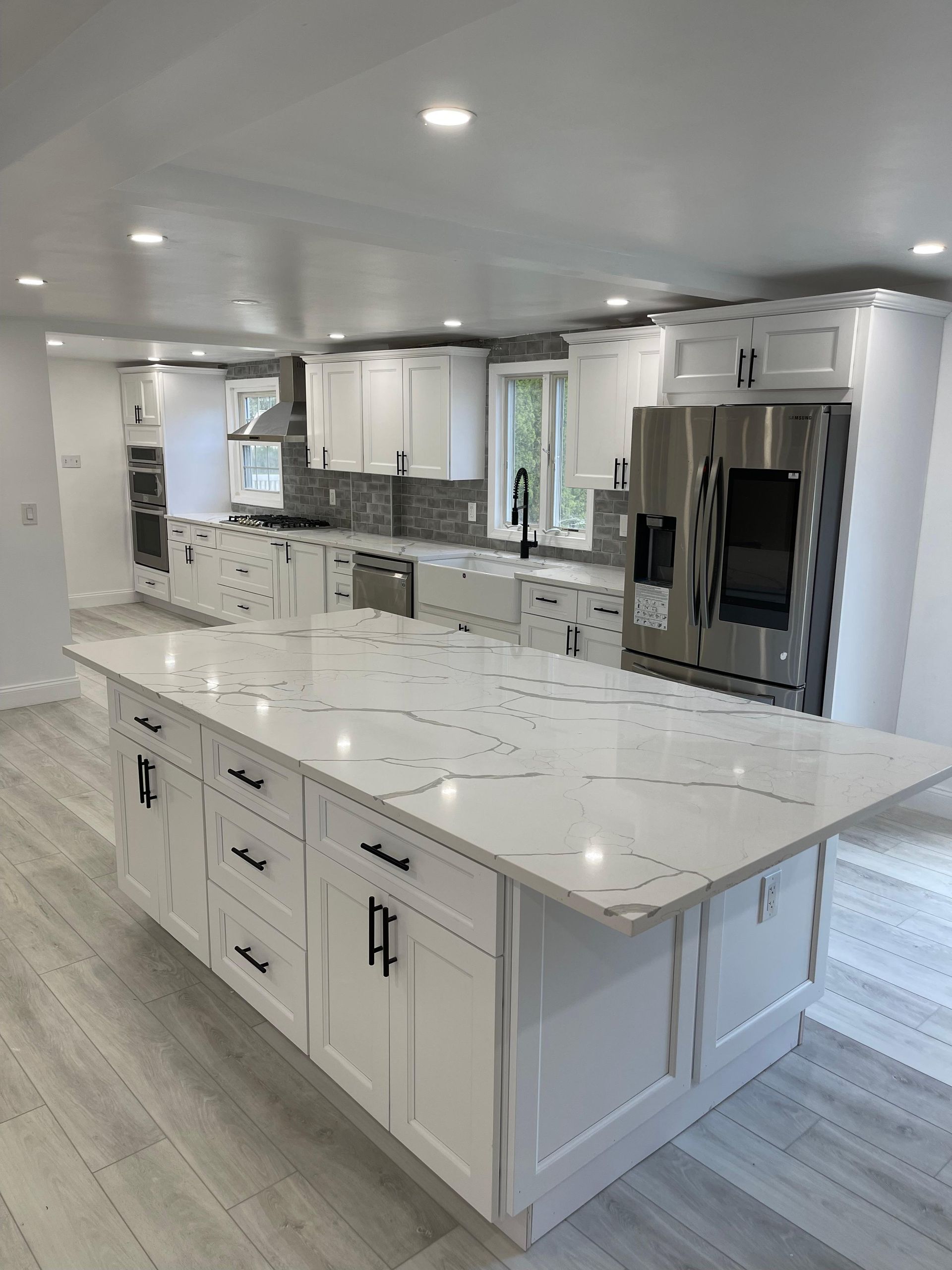Modern kitchen with white cabinets, large island, and stainless steel appliances.
