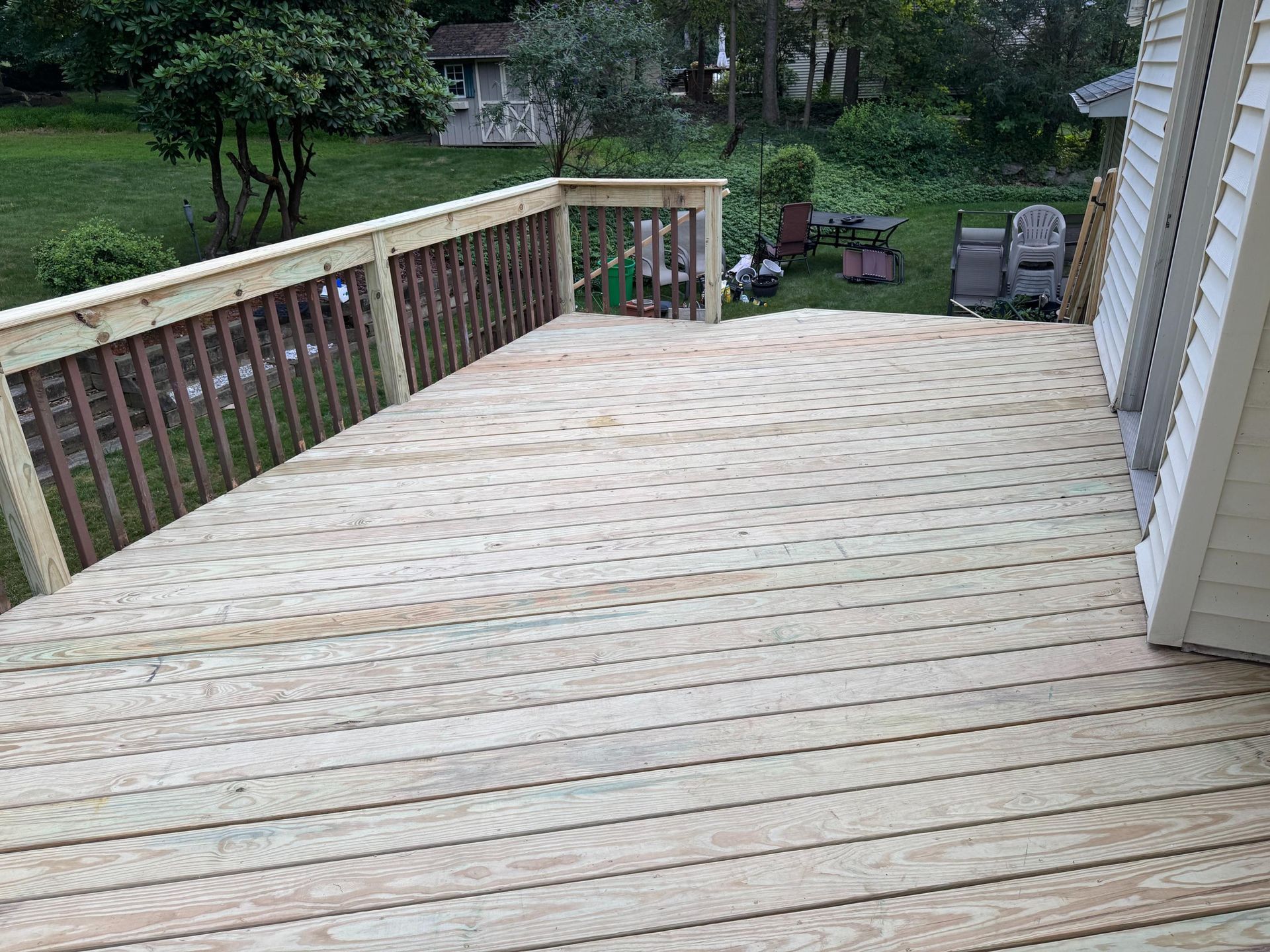 Wooden deck with railing overlooking a grassy yard.