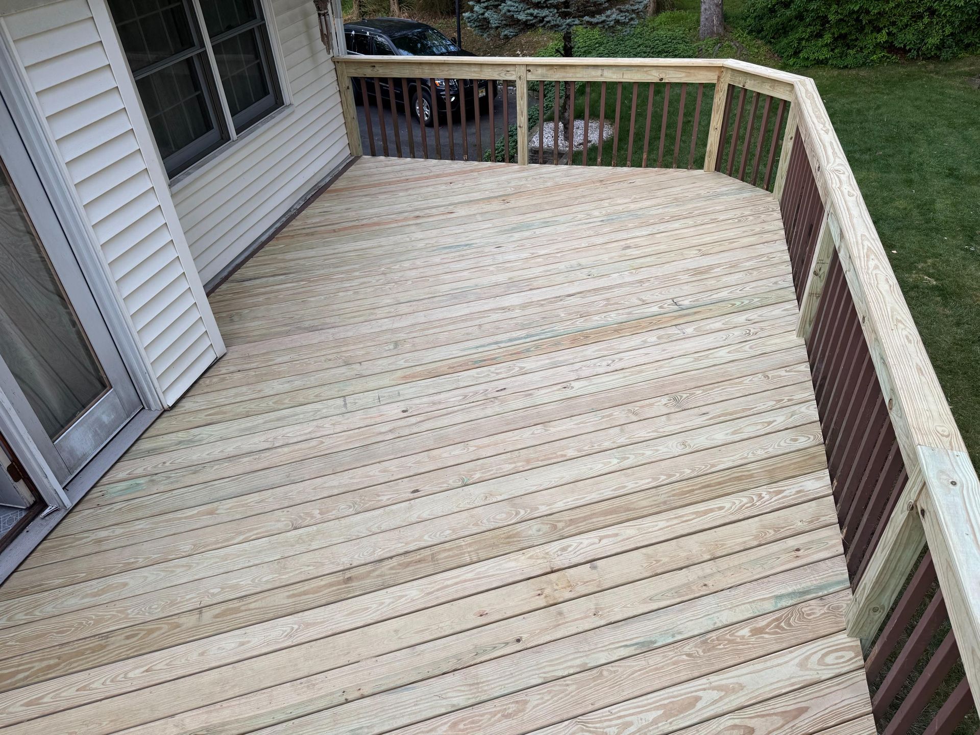 Wooden deck attached to a house with railings.