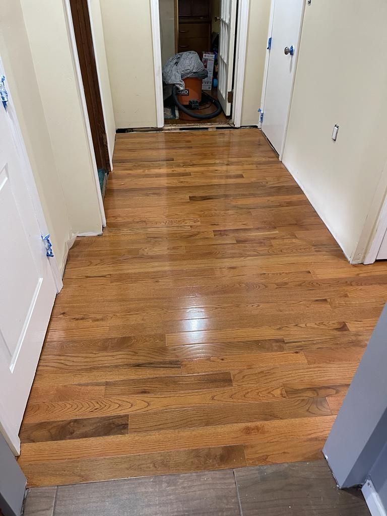 Hallway with refinished hardwood floors, light walls, and white doors.
