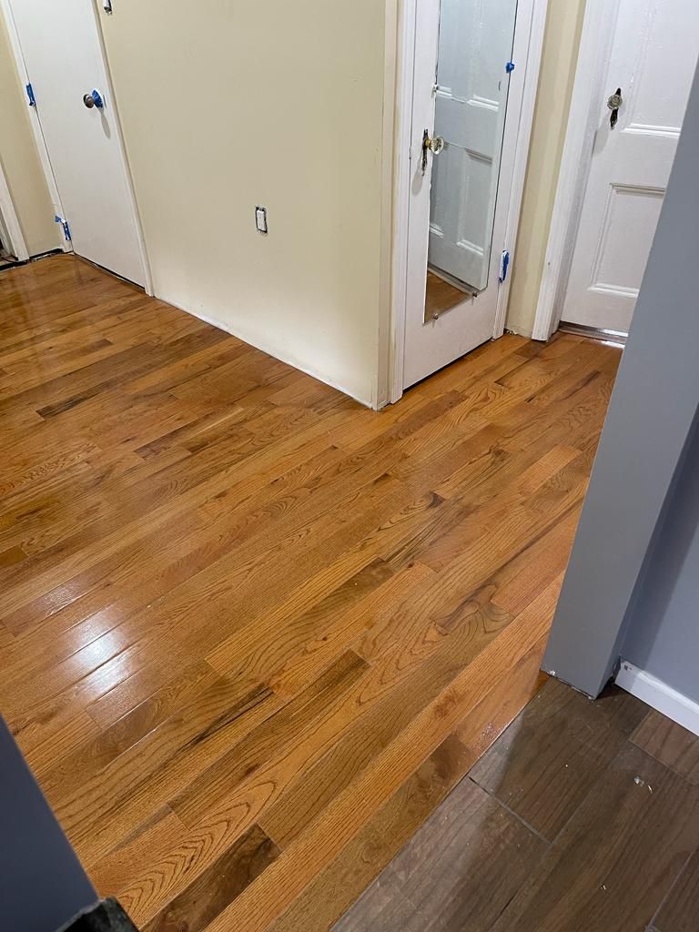 Hardwood floors in a hallway with white walls and doorways.