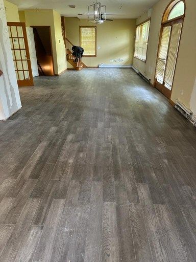 Newly installed wood-look flooring in a room with doors, windows, and stairs.