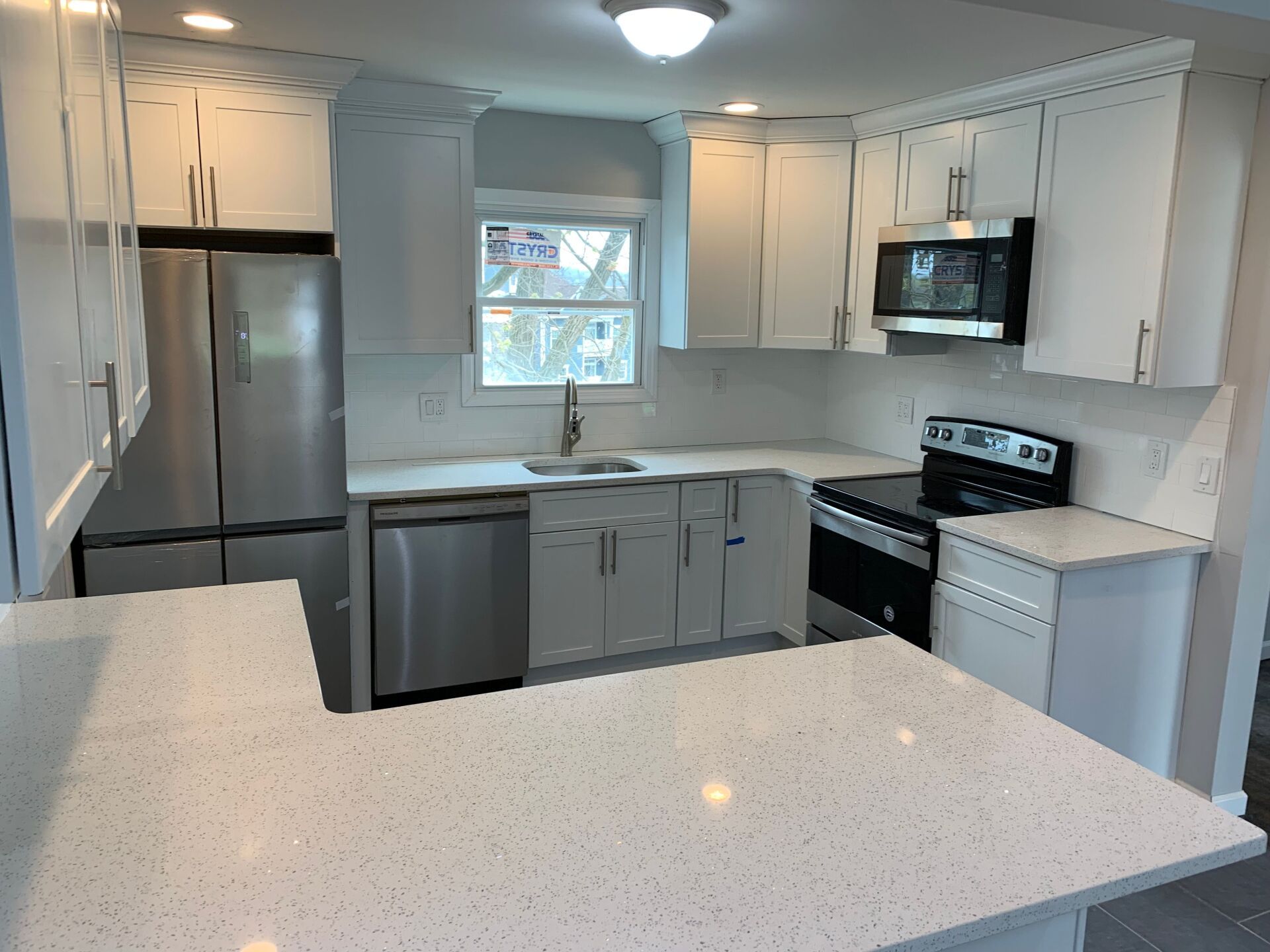 White kitchen with stainless steel appliances, white cabinets, and a quartz countertop.