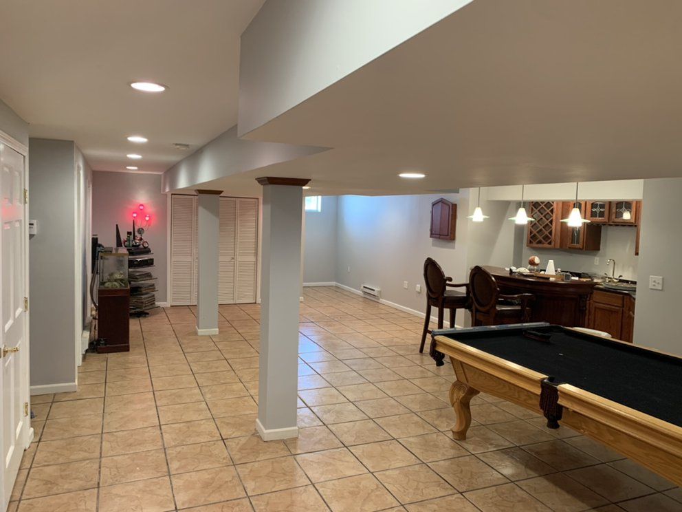 Basement with a pool table, bar, and columns. Beige tile floor, neutral walls, and recessed lighting.