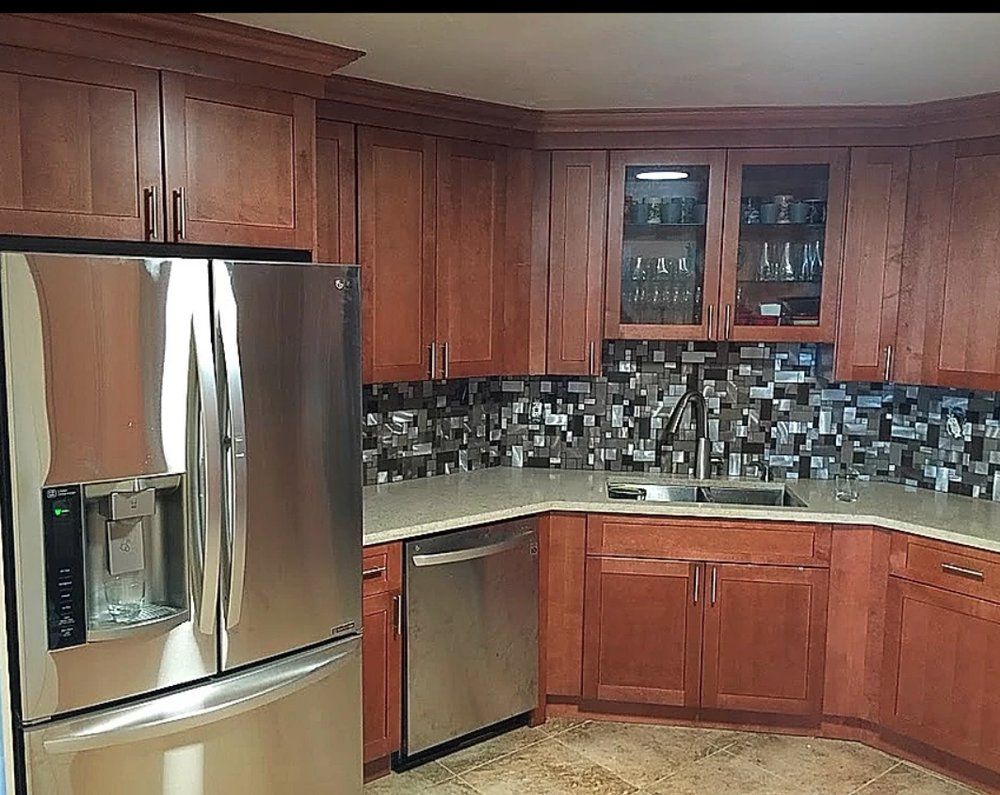 Stainless steel appliances in a kitchen with wooden cabinets and a mosaic backsplash.