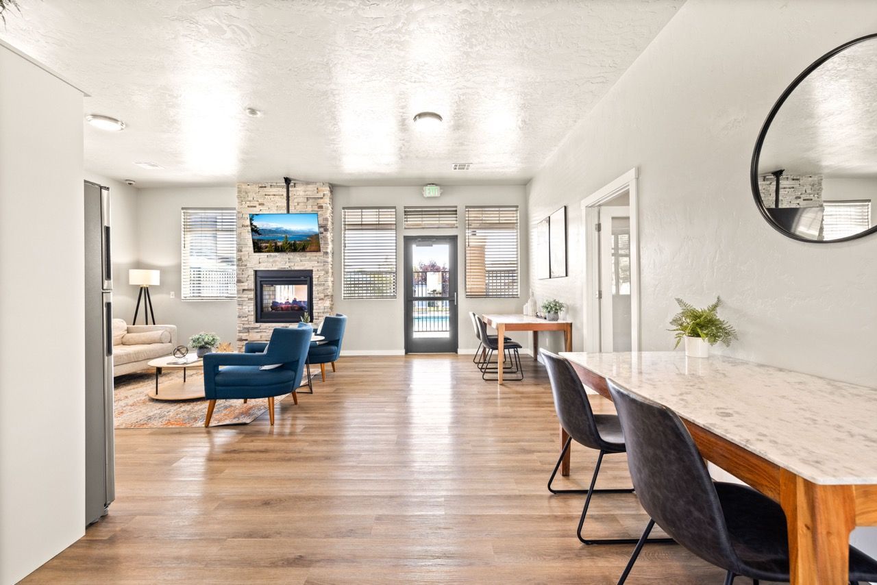 Bright community lounge with fireplace, TV mounted on a stone wall, blue armchairs, and a marble-topped island.