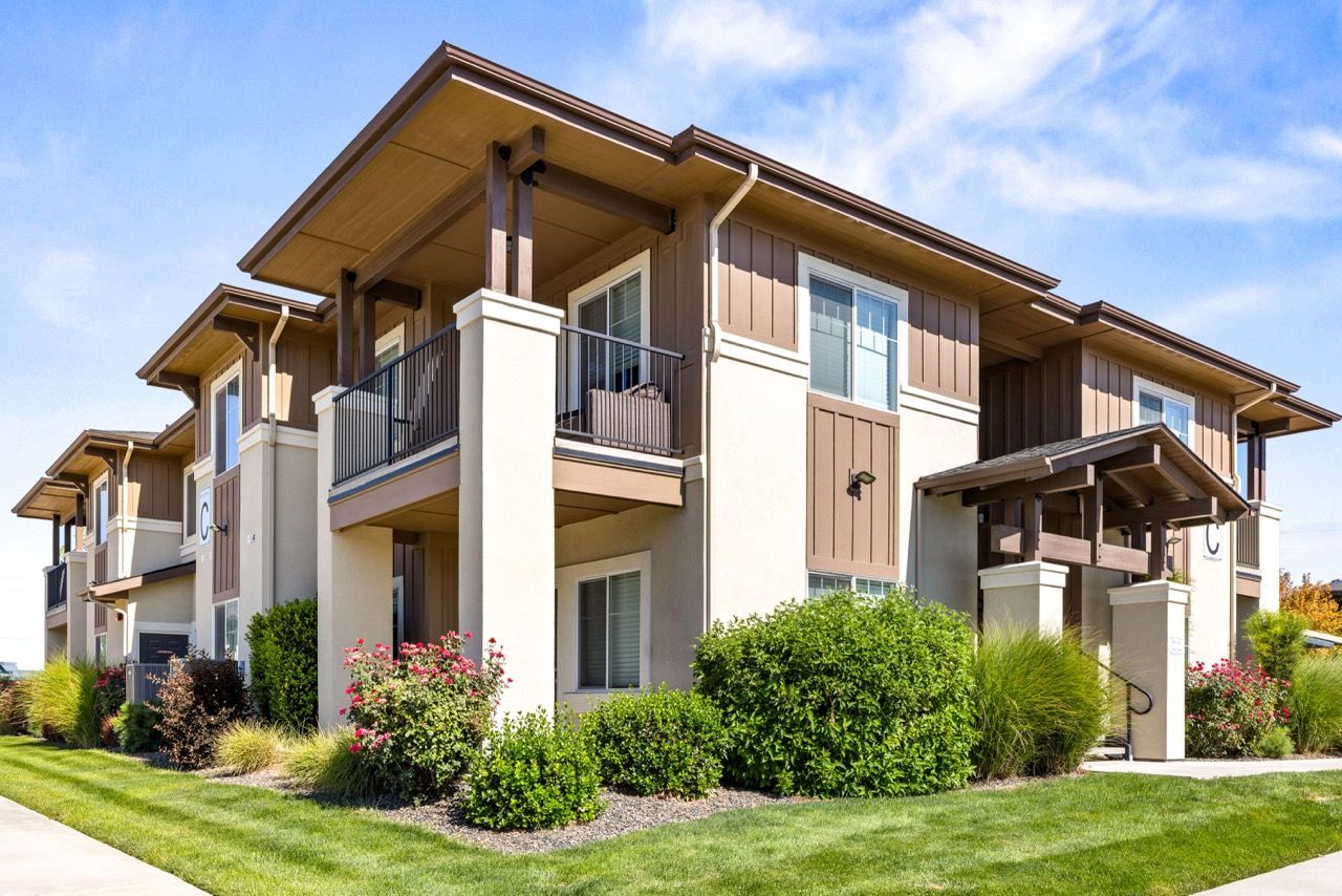 Two-story apartment building exterior with balconies and landscaped grounds.