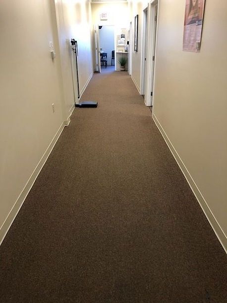 A long hallway with brown carpet and white walls.