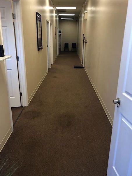 A long hallway with brown carpet and white walls