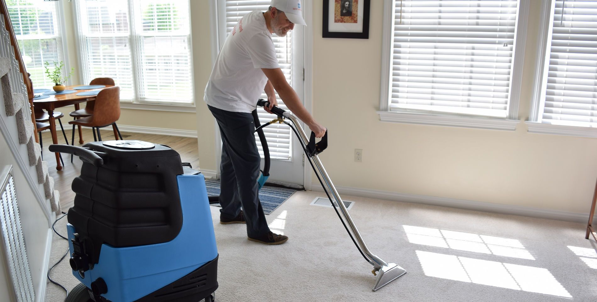 A man is using a vacuum cleaner to clean a carpet in a living room.